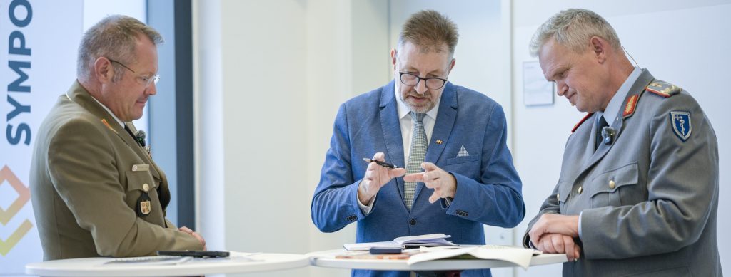 Generalarzt a.D. Dr. Andreas Hölscher, Chefredakteur der „Wehrmedizin und Wehrpharmazie" (Mitte) im Interview mit dem Kommandeur Kommando Sanitätsdienstliche Einsatzversorgung, Generalarzt Dr. Bruno Most (rechts) und dem Vizepräsidenten der Johanniter-Unfall-Hilfe e.V., Professor Dr. Simon Little (links)