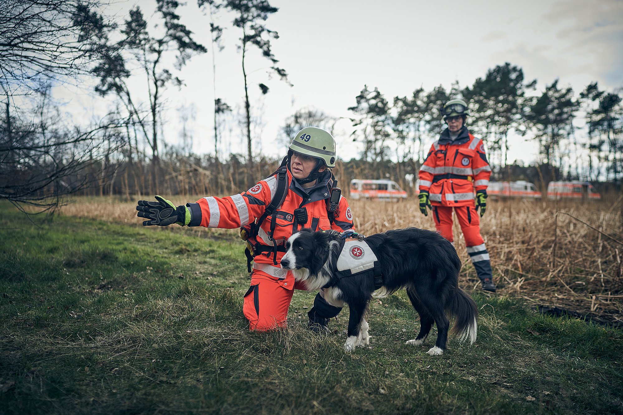 Eine Ehrenamtliche der Rettungshundestaffel weist einem Hund die Richtung.